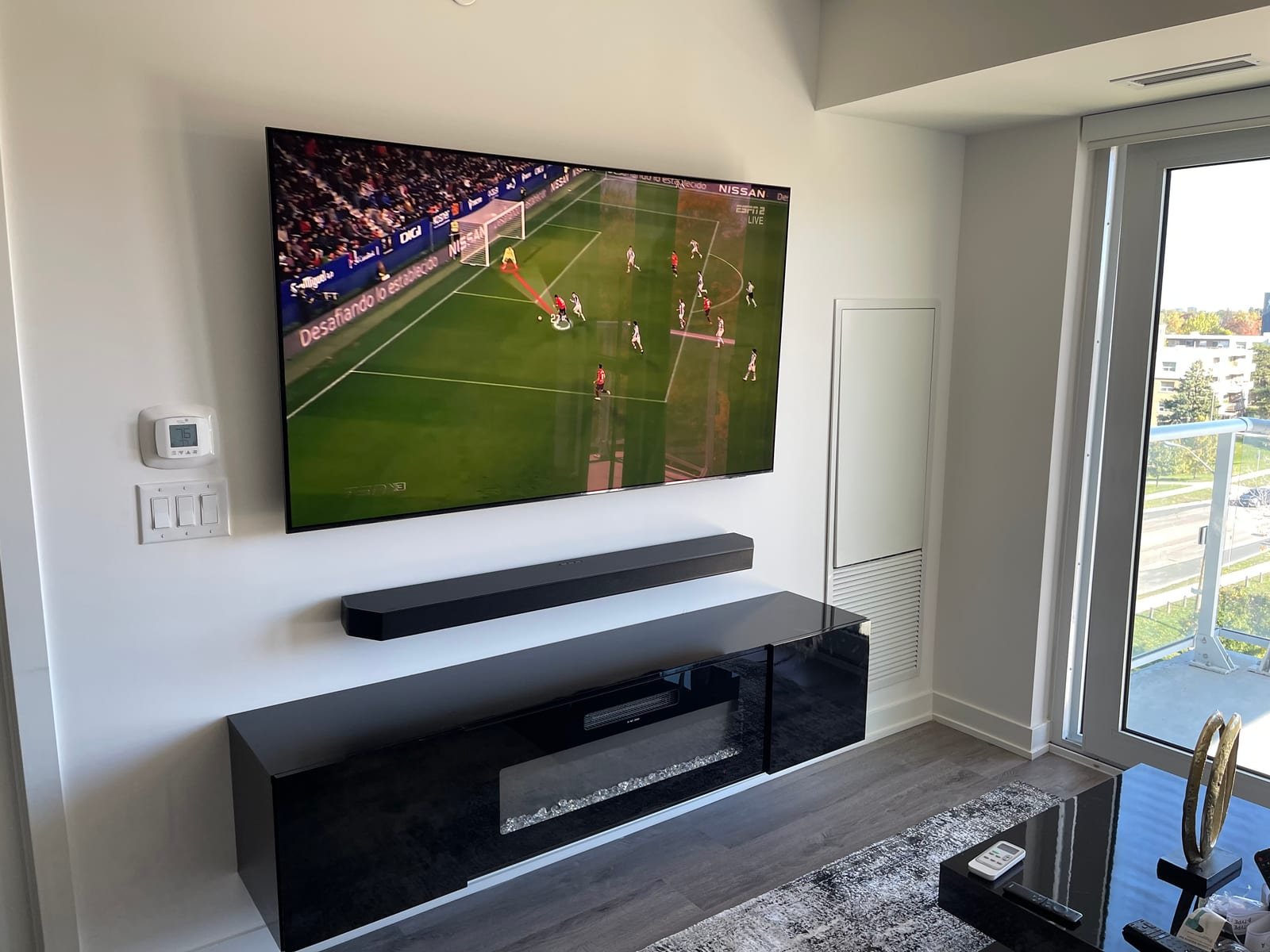 Wall-mounted television and soundbar above a modern fireplace